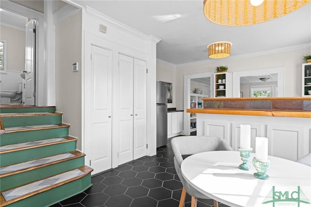 dining room featuring ornamental molding, dark tile patterned floors, and stairs