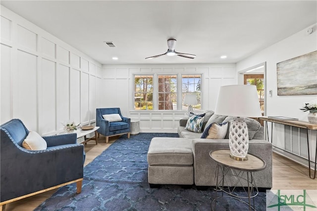 sitting room with a decorative wall, ceiling fan, and wood finished floors