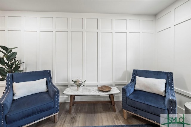 sitting room featuring wood finished floors and a decorative wall