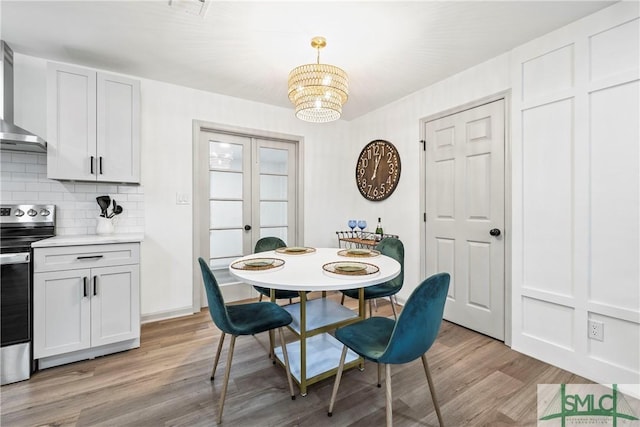 dining area with light wood finished floors, french doors, an inviting chandelier, and baseboards