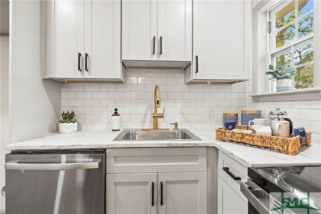 kitchen featuring light stone countertops, white cabinetry, a sink, and stainless steel dishwasher