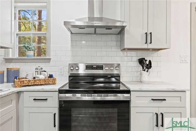 kitchen featuring wall chimney range hood, white cabinets, and electric stove