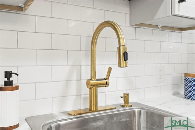 details featuring decorative backsplash, light stone counters, and a sink