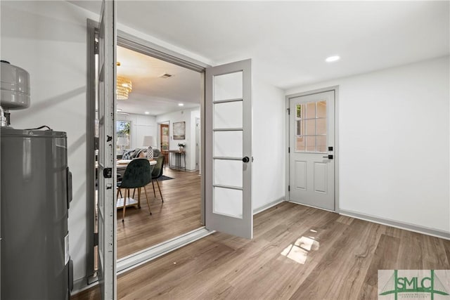 interior space with wood finished floors, recessed lighting, baseboards, and electric water heater