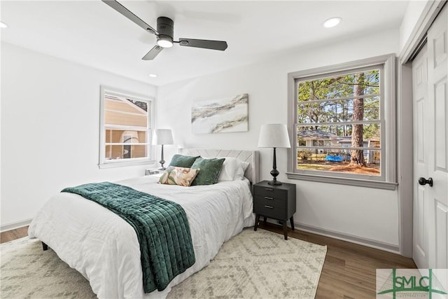 bedroom featuring wood finished floors, baseboards, multiple windows, and recessed lighting