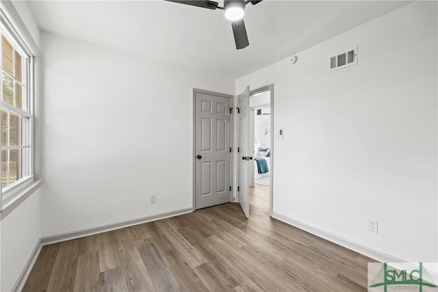 unfurnished room with light wood-type flooring, baseboards, a ceiling fan, and visible vents