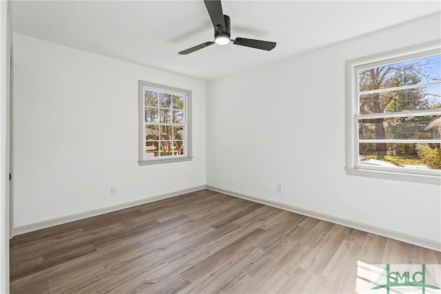 empty room featuring plenty of natural light, ceiling fan, baseboards, and wood finished floors