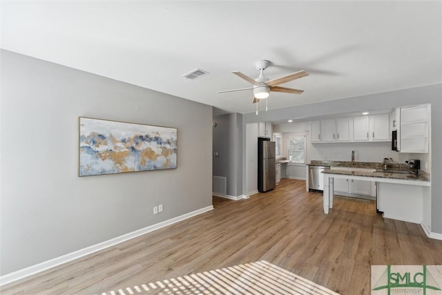 kitchen with sink, light wood-type flooring, stainless steel appliances, white cabinetry, and ceiling fan