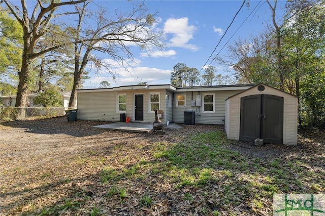 rear view of house with central air condition unit, a shed, and a patio