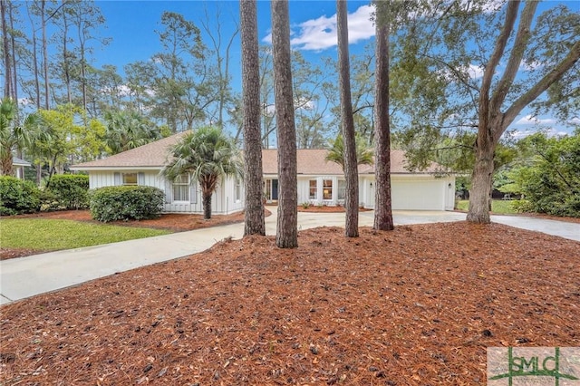 ranch-style house with board and batten siding, an attached garage, and driveway