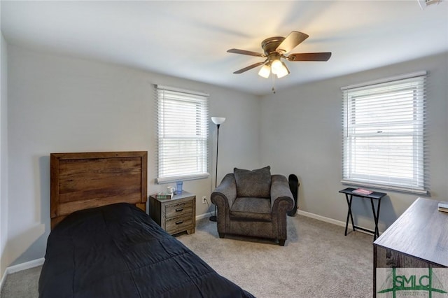 bedroom with baseboards, multiple windows, light carpet, and a ceiling fan