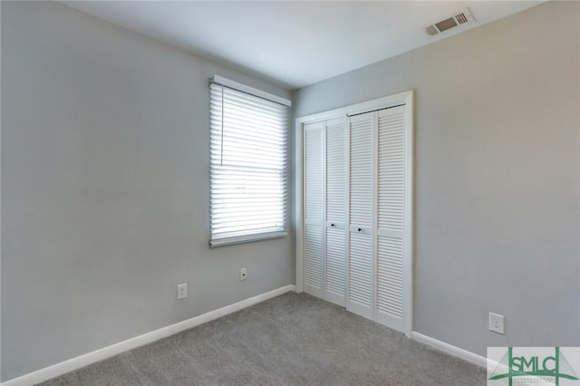 unfurnished bedroom with baseboards, visible vents, light colored carpet, and a closet