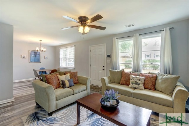 living area with baseboards, visible vents, ceiling fan with notable chandelier, and wood finished floors