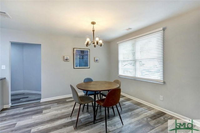 dining space with dark wood finished floors, visible vents, baseboards, and a notable chandelier