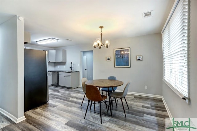 dining area featuring baseboards, an inviting chandelier, visible vents, and wood finished floors