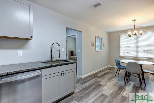 kitchen featuring stainless steel dishwasher, visible vents, hanging light fixtures, a sink, and dark wood-style floors