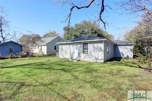 back of property featuring fence, entry steps, and a yard