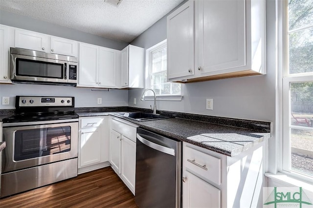 kitchen featuring a sink, dark wood-style floors, appliances with stainless steel finishes, white cabinetry, and a textured ceiling