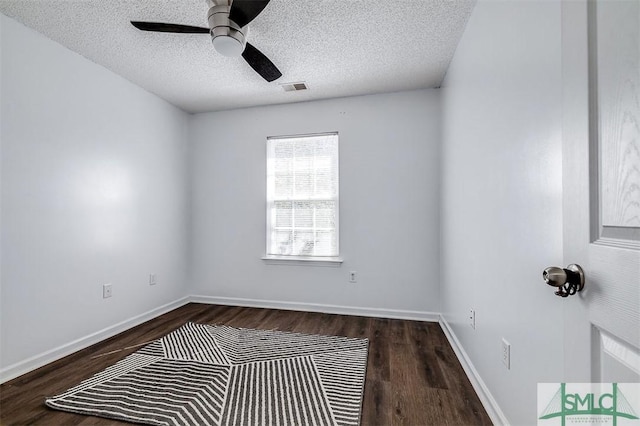 unfurnished room with a textured ceiling, visible vents, baseboards, and dark wood-style flooring