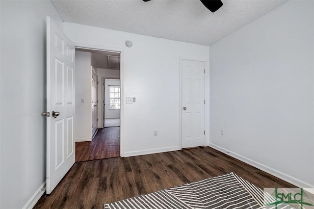 unfurnished bedroom featuring dark wood finished floors, baseboards, a ceiling fan, and a textured ceiling