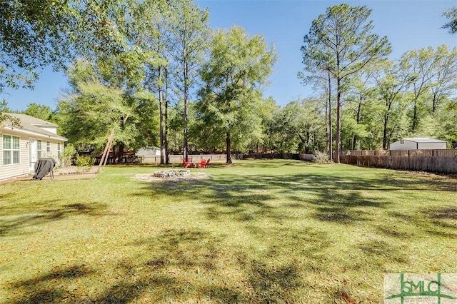 view of yard with a fenced backyard and a fire pit