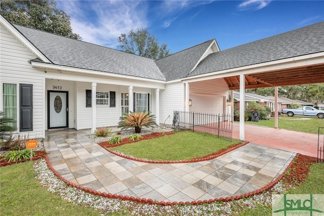 view of front of property with roof with shingles, a front yard, an attached carport, and driveway