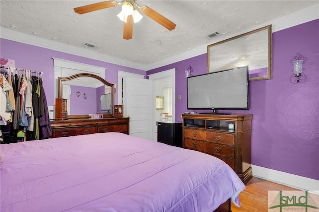 bedroom with a textured ceiling, light wood finished floors, visible vents, and baseboards