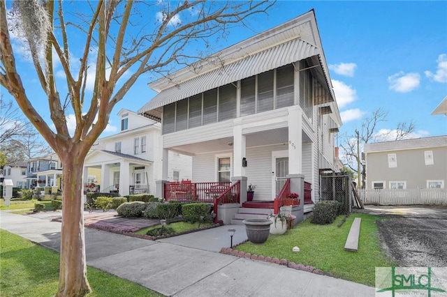 view of front facade featuring a porch, a front yard, fence, and a residential view