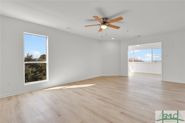 empty room featuring light wood-style floors, visible vents, ceiling fan, and baseboards