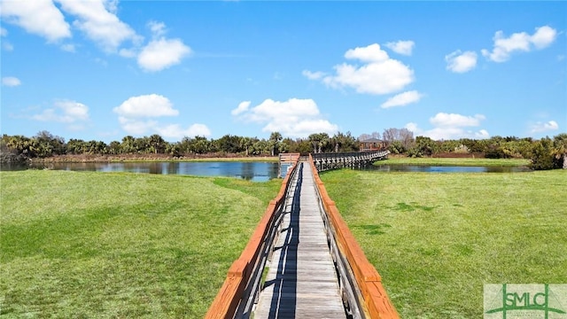 view of dock with a lawn and a water view