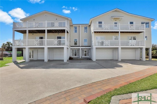 rear view of house featuring driveway, an attached garage, and a balcony