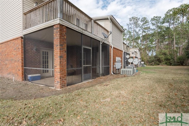 exterior space with a balcony, a sunroom, a lawn, and brick siding