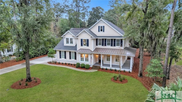 view of front of property with a porch, a standing seam roof, metal roof, driveway, and a front lawn