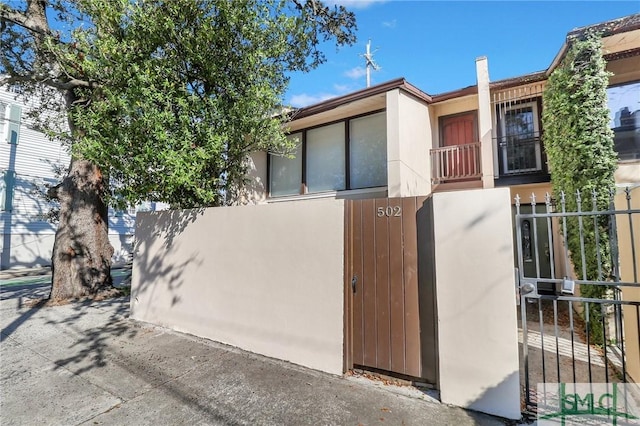 view of front of home featuring fence, a balcony, and stucco siding