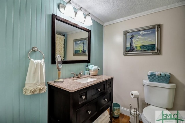 bathroom featuring toilet, ornamental molding, vanity, a textured ceiling, and baseboards