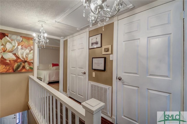 hallway with a chandelier, a textured ceiling, and visible vents