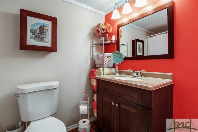 bathroom featuring toilet, ornamental molding, vanity, and baseboards