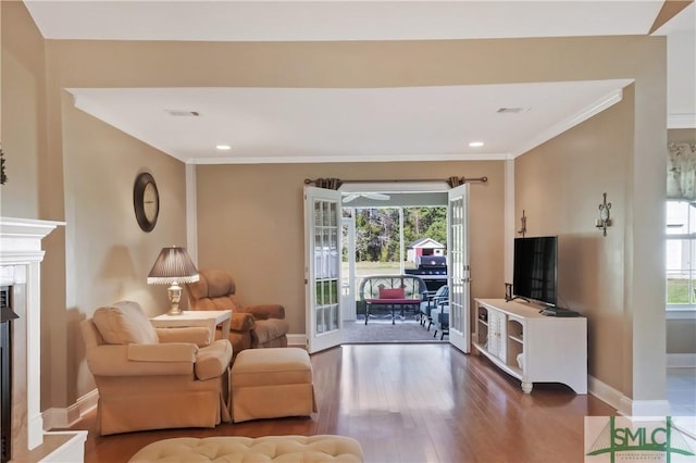 living area with a healthy amount of sunlight, crown molding, baseboards, and wood finished floors