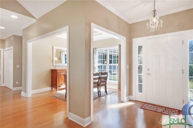 foyer entrance featuring recessed lighting, light wood-style flooring, ornamental molding, a chandelier, and baseboards