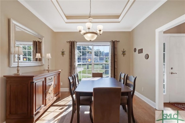 dining room with light wood finished floors, baseboards, a tray ceiling, and a chandelier