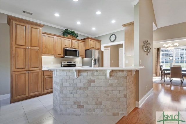 kitchen featuring crown molding, a breakfast bar area, light countertops, visible vents, and appliances with stainless steel finishes