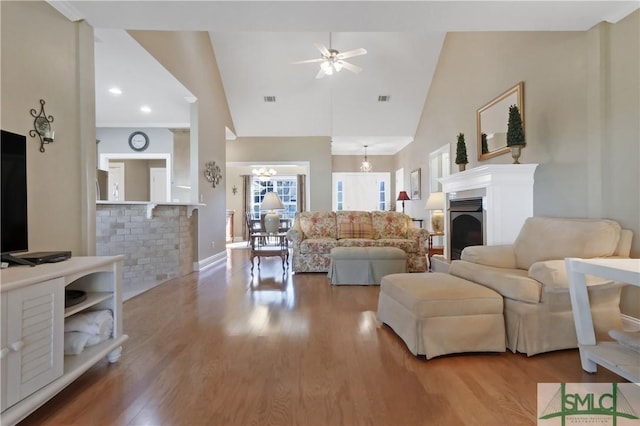 living room with baseboards, visible vents, ceiling fan, wood finished floors, and a fireplace