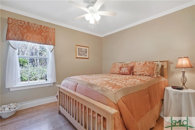 bedroom featuring a ceiling fan, crown molding, baseboards, and wood finished floors