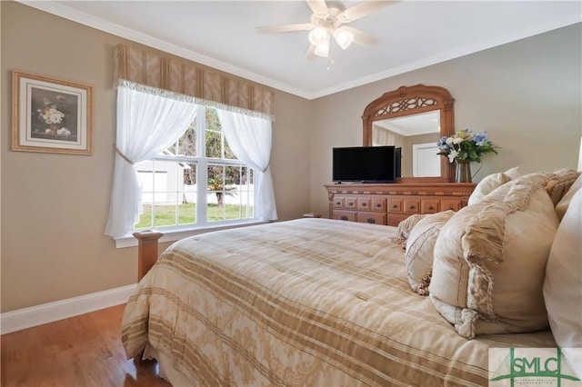 bedroom with baseboards, ceiling fan, wood finished floors, and crown molding