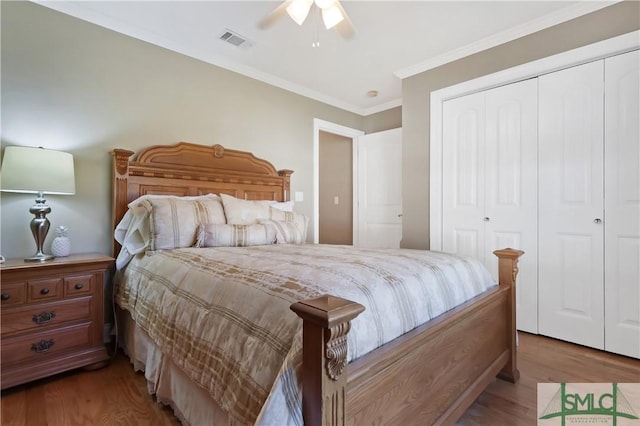 bedroom with a closet, visible vents, crown molding, and wood finished floors