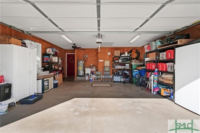 garage with wood walls, ceiling fan, a garage door opener, and electric water heater