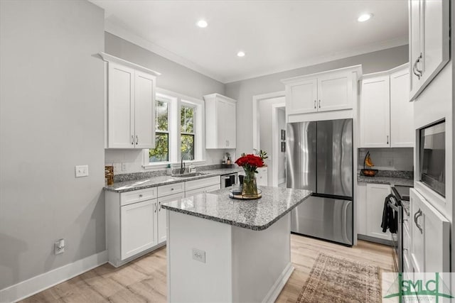 230 Blackjack Oak Dr W, Richmond Hill, GA 31324 - kitchen with stainless steel appliances, light wood-style flooring, light stone countertops, white cabinetry, and decorative backsplash