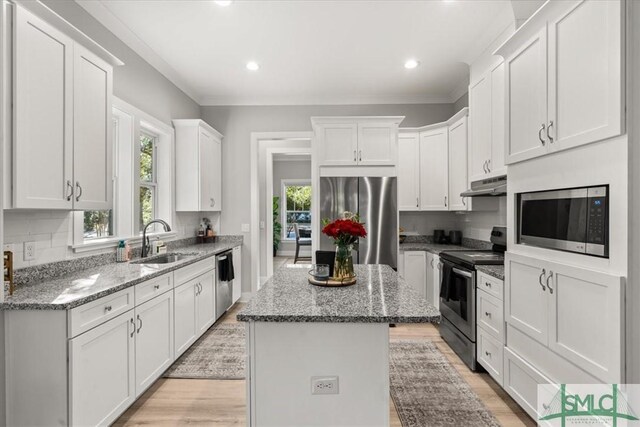230 Blackjack Oak Dr W, Richmond Hill, GA 31324 - kitchen with appliances with stainless steel finishes, under cabinet range hood, a kitchen island, white cabinets, and light wood-style floors