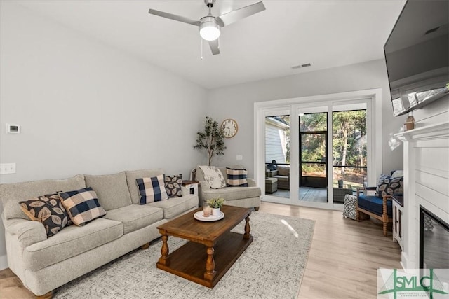 230 Blackjack Oak Dr W, Richmond Hill, GA 31324 - living area with a glass covered fireplace, light wood-type flooring, and a ceiling fan