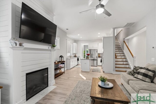 230 Blackjack Oak Dr W, Richmond Hill, GA 31324 - living area featuring stairway, light wood-style floors, ceiling fan, a glass covered fireplace, and recessed lighting